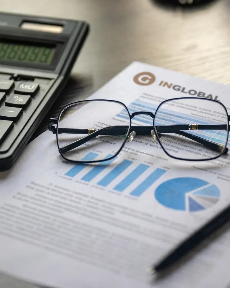 Calculadora, anteojos e informe financiero sobre un escritorio